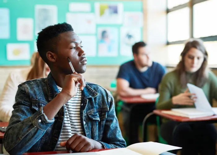 Shot of a young man looking thoughtful at his desk in a classroom at university