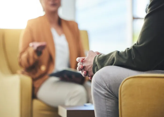 Man, hands and listening for therapy, sofa or advice from woman for mental health, psychology or care. Psychiatrist, patient and frustrated in clinic, session or couch for help, anxiety or depression