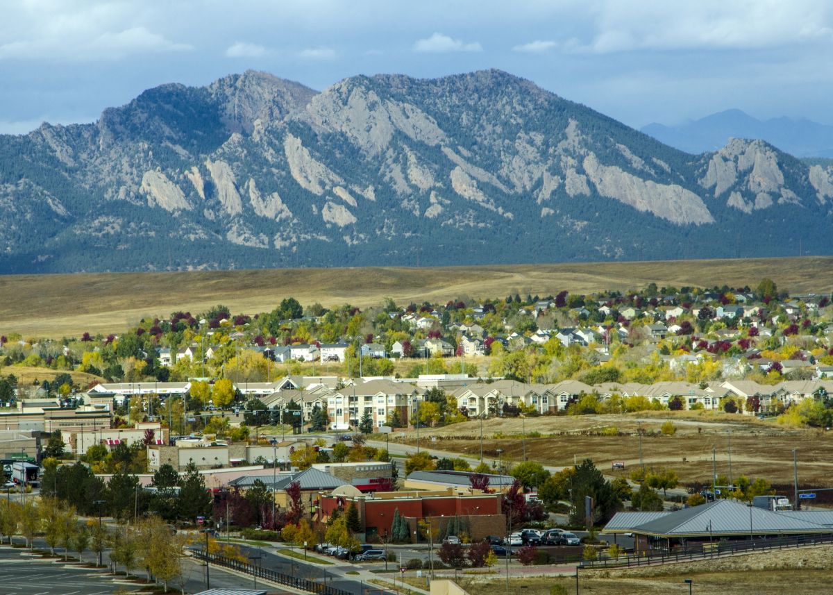Broomfield, Colorado, USA - October 19, 2015: Urban sprawl from the developments in Broomfield, Colorado apprach the majestic range of the Flatiron Mountains. Carpenters work on a new sledding attraction at the top of Vail Mountain which overlooks the Col