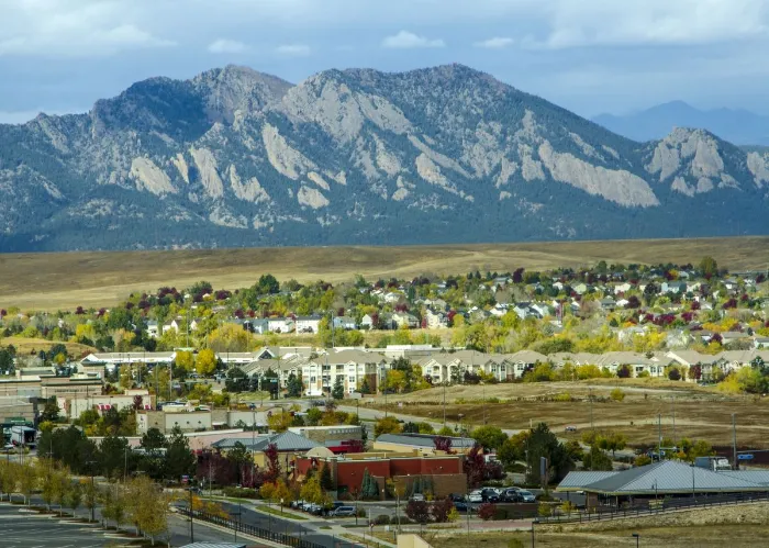Broomfield, Colorado, USA - October 19, 2015: Urban sprawl from the developments in Broomfield, Colorado apprach the majestic range of the Flatiron Mountains. Carpenters work on a new sledding attraction at the top of Vail Mountain which overlooks the Col
