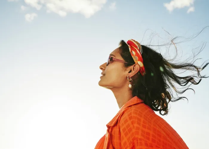 Side view of a young woman looking up at the sky and smiling during a sunny day in summer