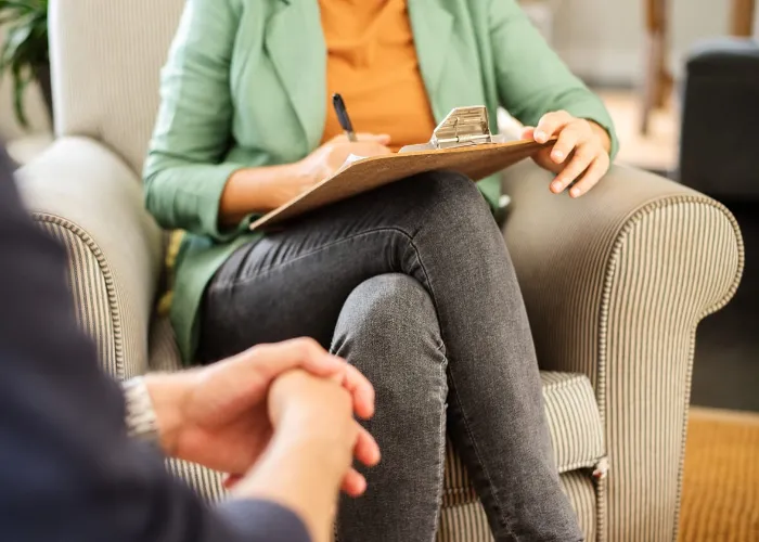 Close-up of a mental health counselor taking notes during a therapy session with a client in her office
